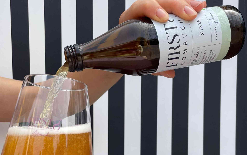 Kombucha Minze in Weinglas vor gestreiftem Hintergrund